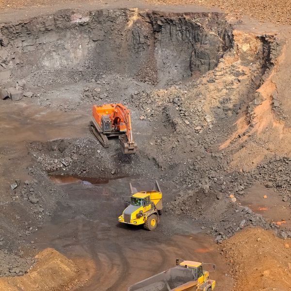 Manganese mining with orange excavator & yellow rock trucks