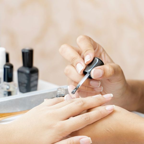 Manicurist hand painting nails of client.