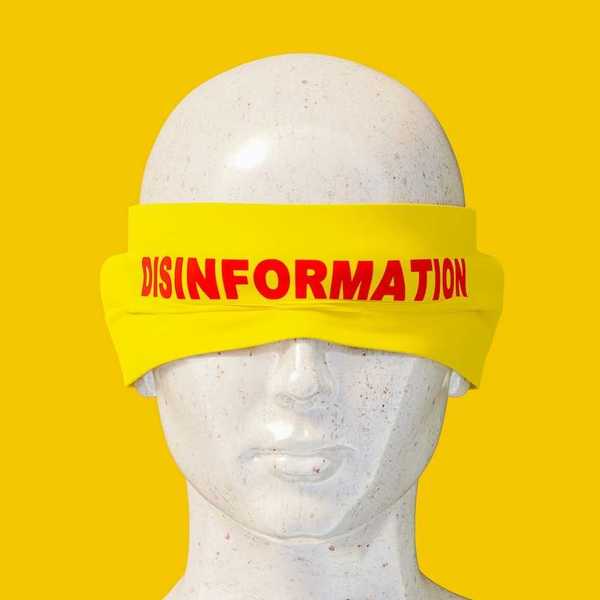 Mannequin head shot wearing a yellow blindfold labeled "disinformation" in red letters.