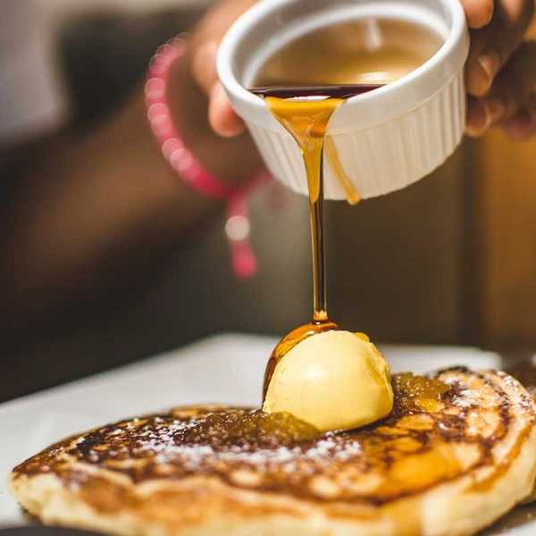 Maple syrup being poured over pancakes
