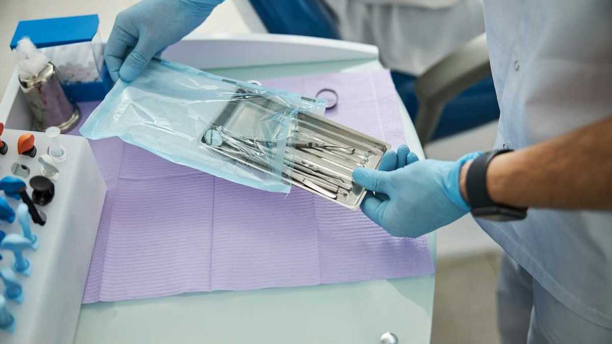 Medical professional wearing blue surgical gloves removes sterilized tools from protective sealed bag.