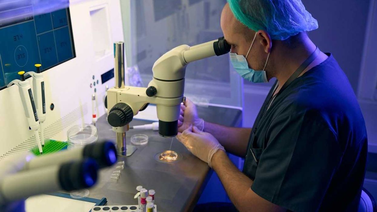 Medical scientist peering though laboratory microscope