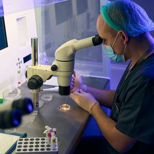 Medical scientist peering though laboratory microscope