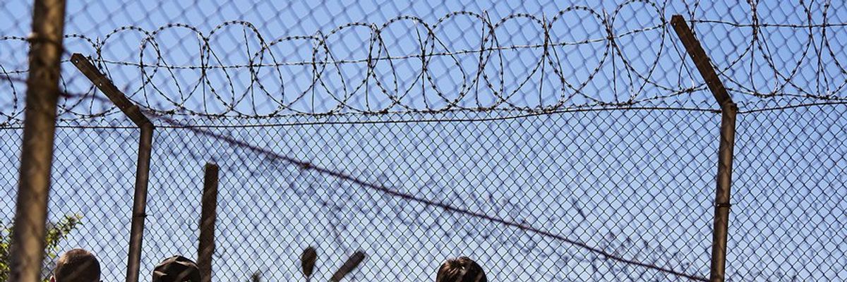 Men standing behind barbed wire fences.