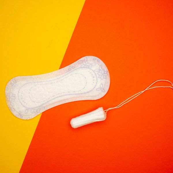 Menstrual pad and tampon against a yellow and orange background.