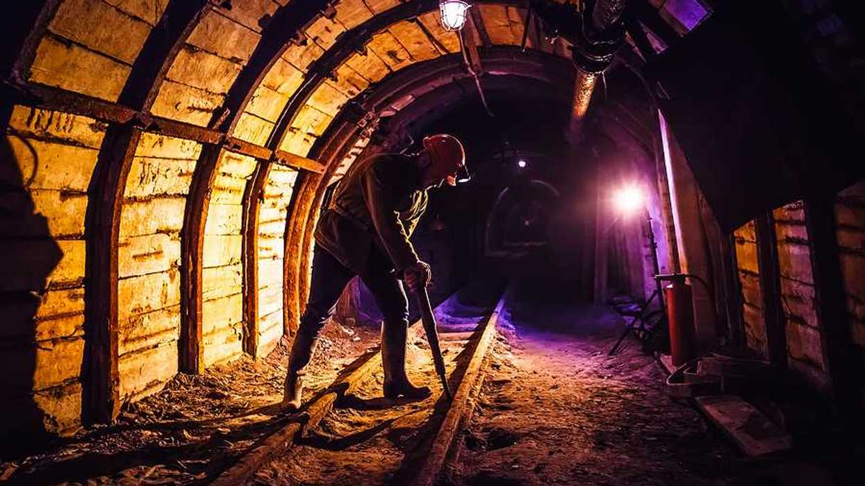Miner working a jackhammer in a coal mine.