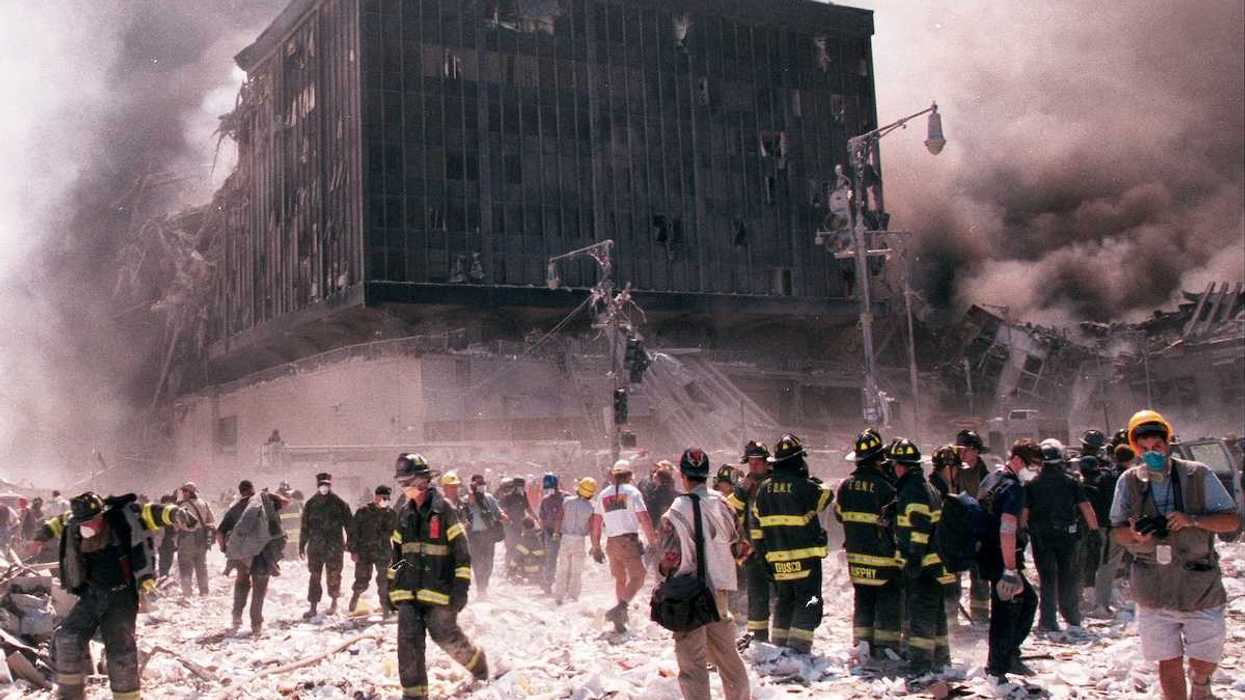 New York City firefighters and journalists stand near the area known as Ground Zero after the collapse of the Twin Towers September 11, 2001 in New York City.