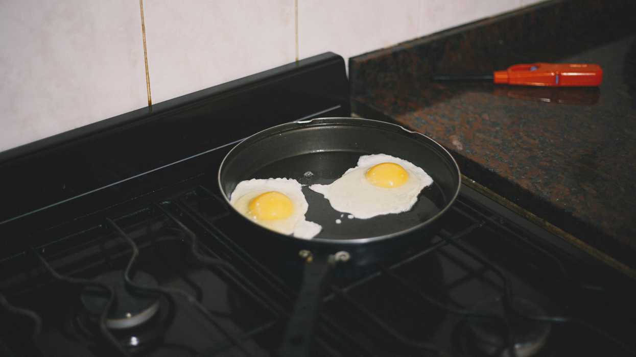 Non-stick pan on stovetop with fried eggs inside.