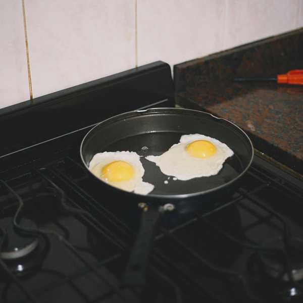 Non-stick pan on stovetop with fried eggs inside.