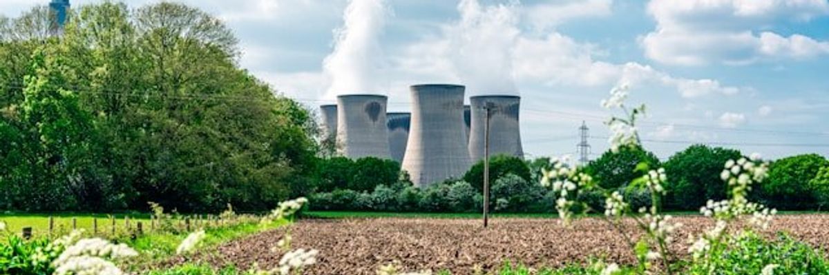 Nuclear reactor towers next to a farm field.