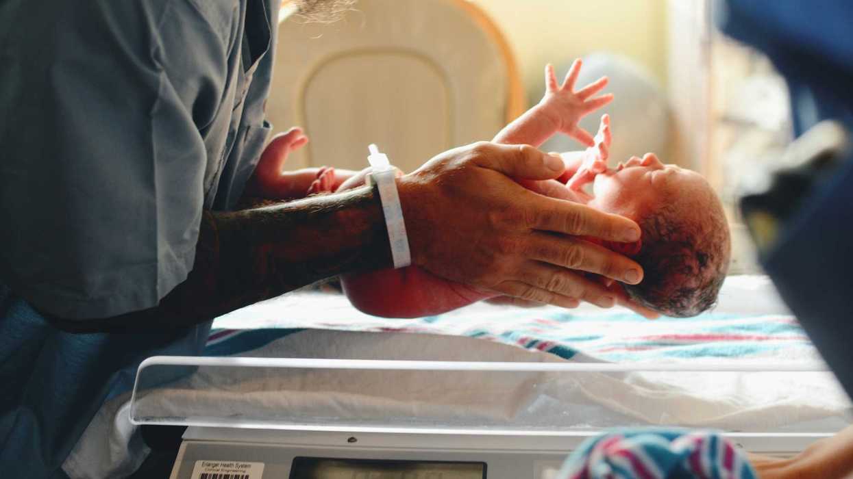 Nurse wearing gray shirt putting baby on scale