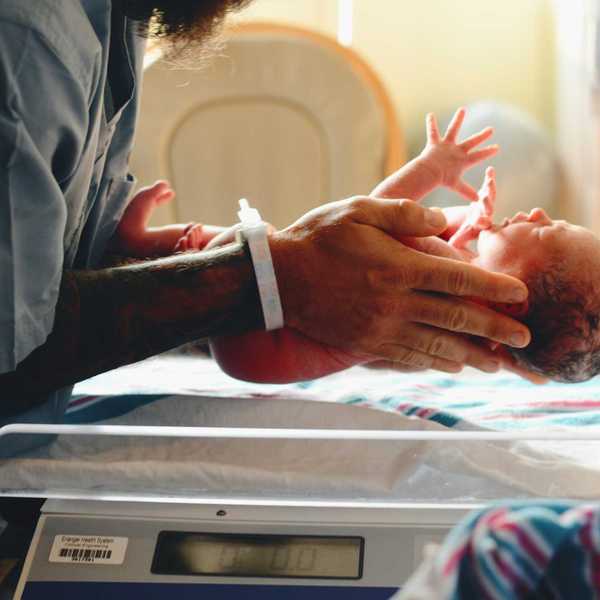 Nurse wearing gray shirt putting baby on scale