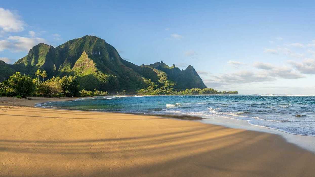 Ocean lapping a sandy South Pacific beach with verdant hills behind