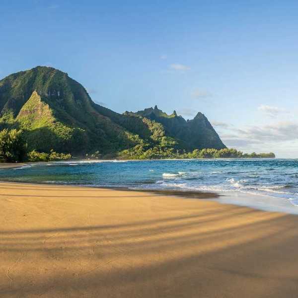 Ocean lapping a sandy South Pacific beach with verdant hills behind