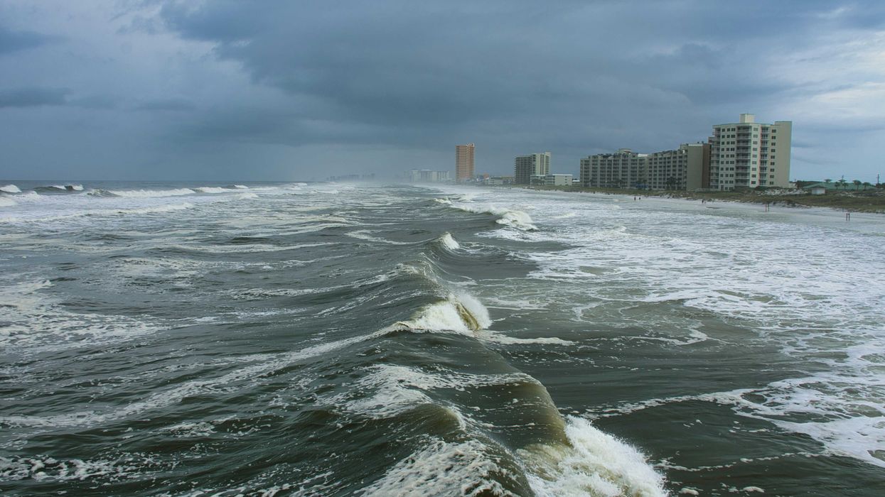 ocean waves near city buildings during daytime