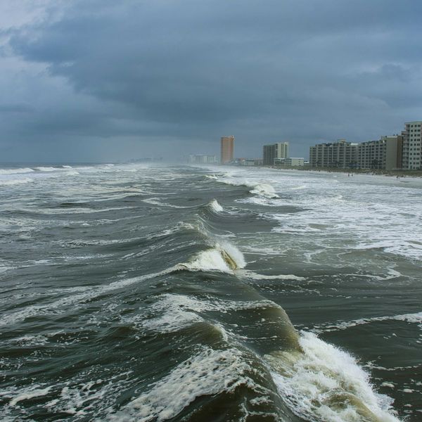 ocean waves near city buildings during daytime