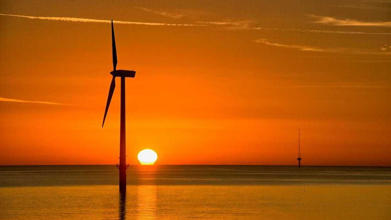 Offshore wind turbine silouetted against setting sun