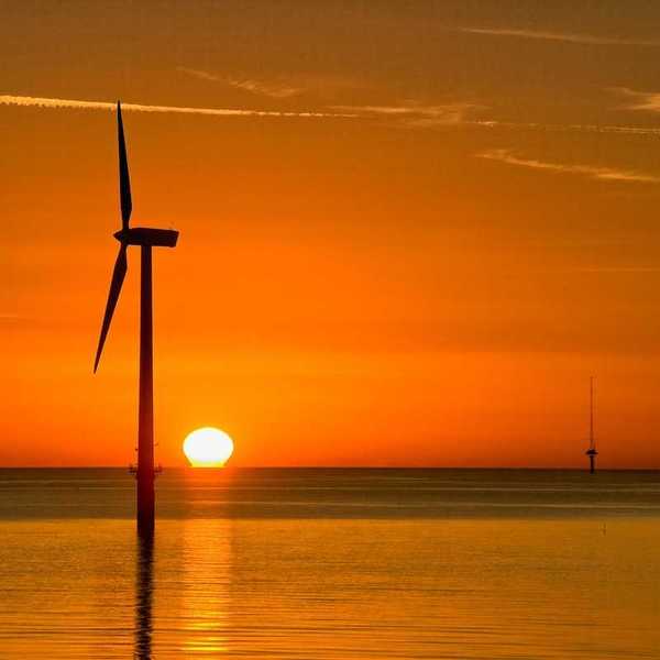 Offshore wind turbine silouetted against setting sun