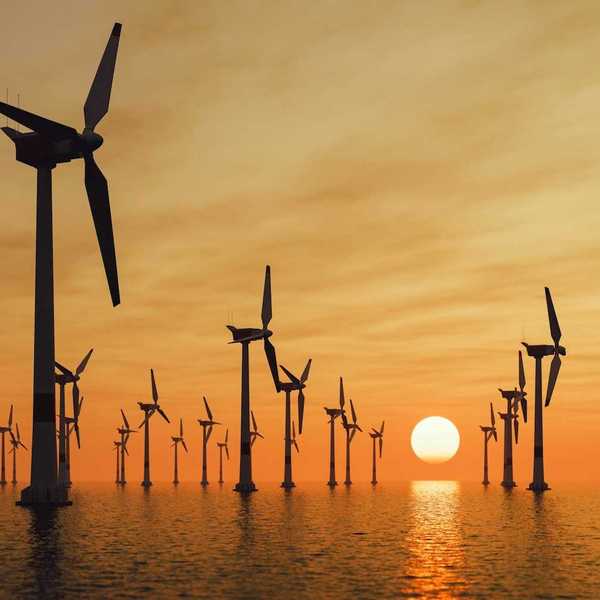 Offshore wind turbines against a setting sun
