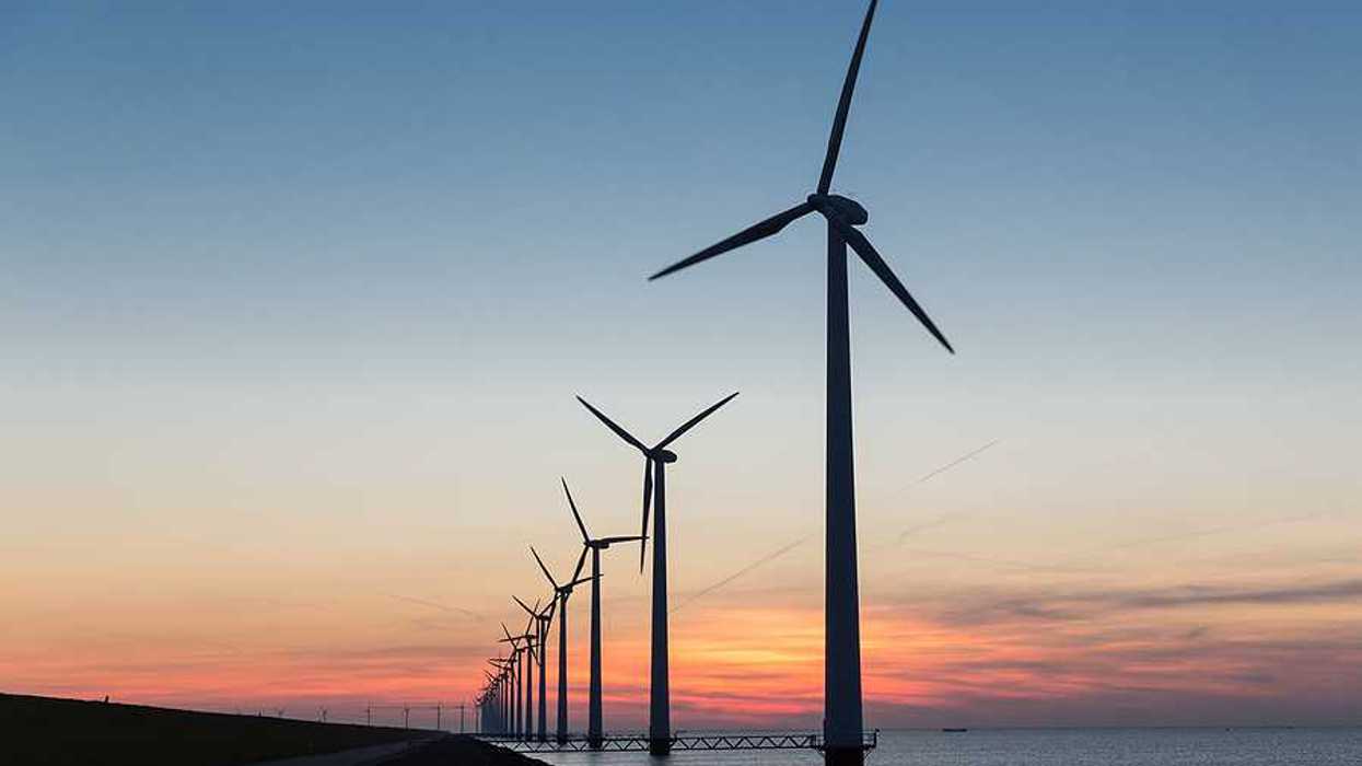Offshore wind turbines stretching into the distance at sunset