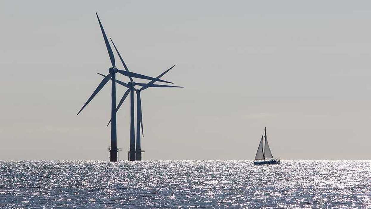 Offshore wind turbines with a sailboat in the foreground
