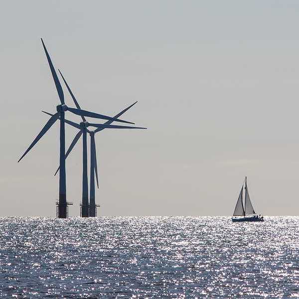 Offshore wind turbines with a sailboat in the foreground