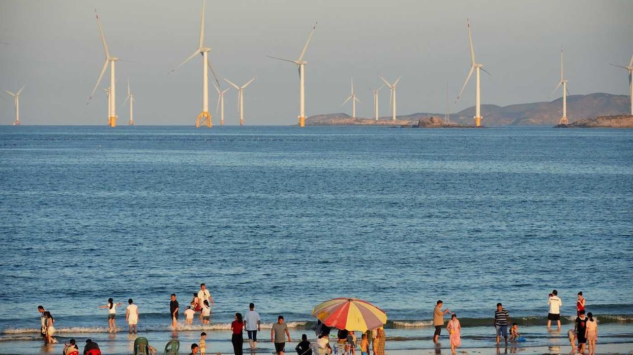 Offshore wind turbines with beachgoers in foreground