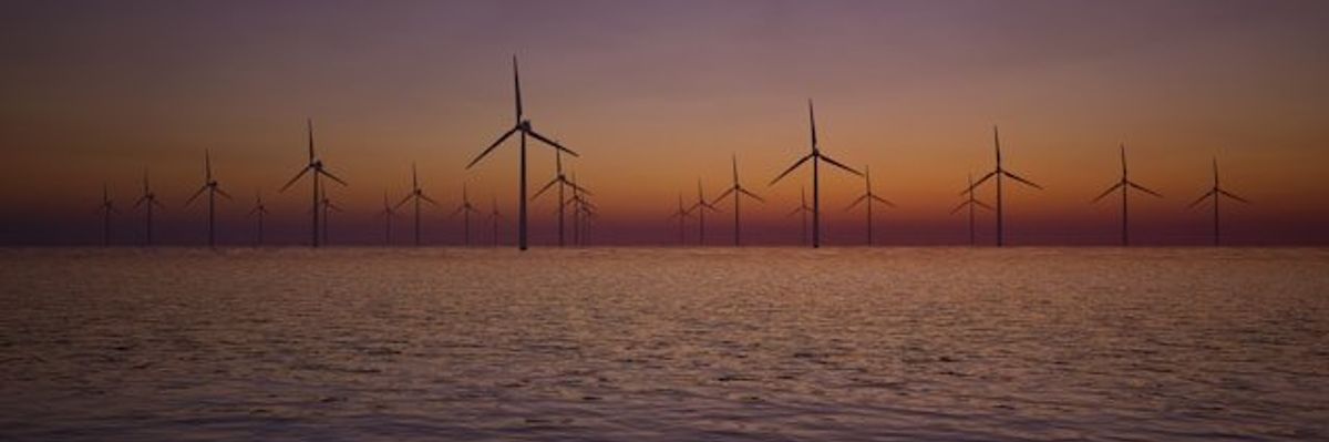 Offshore wind turbines with the sunset in the background.