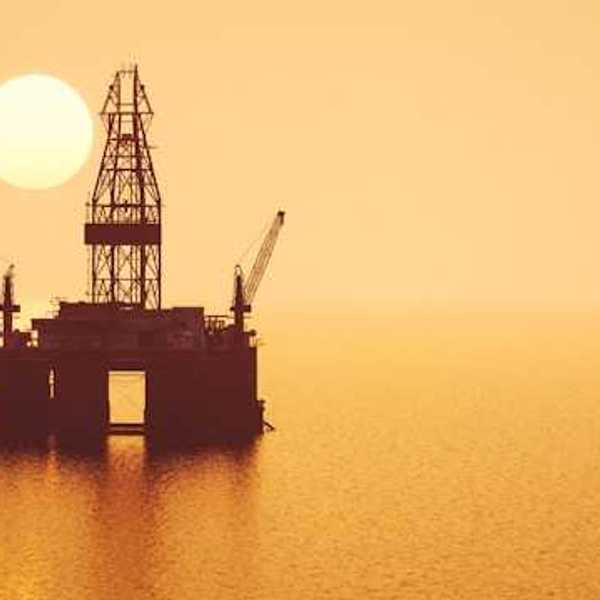 Oil and gas equipment on the ocean with the sun in the background
