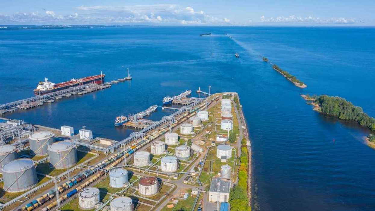 Oil and gas export terminal tanker at dock and multiple storage tanks adjacent to a large waterbody