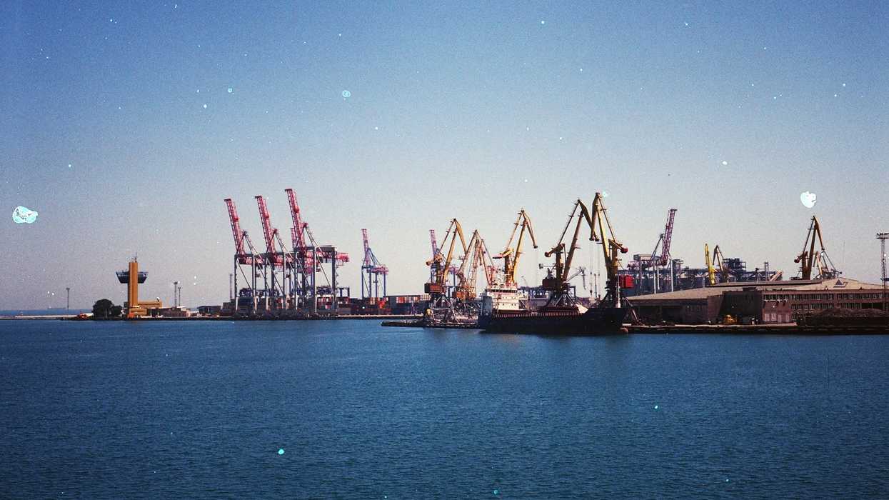 Oil export ships and cranes at a dock in the daytime.