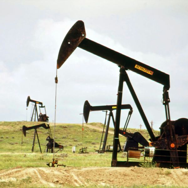 Oil pumps sitting on a green field.