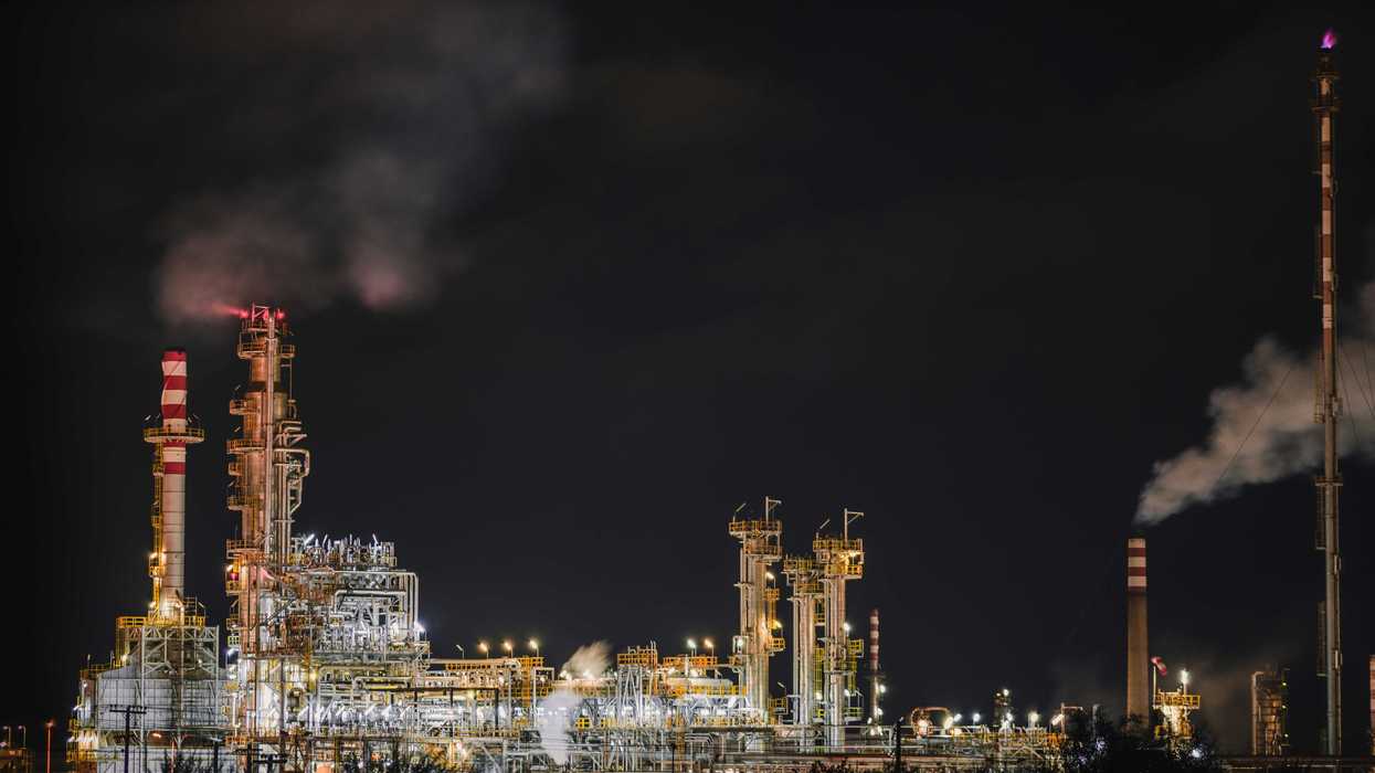 Oil refinery illuminated at night spewing pollution.