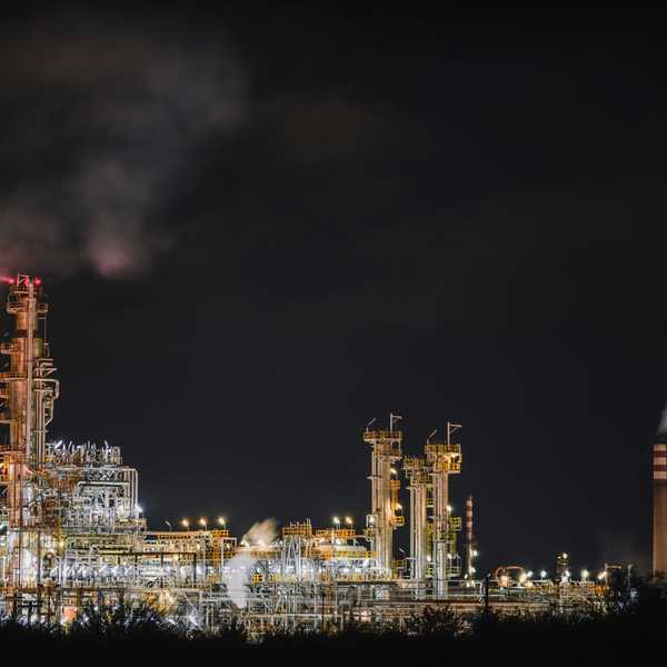 Oil refinery illuminated at night spewing pollution.
