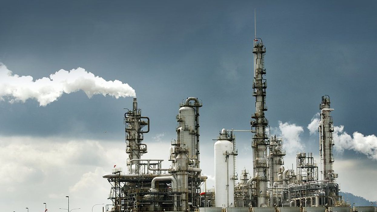 Oil refinery with smoke billowing from smokestacks.