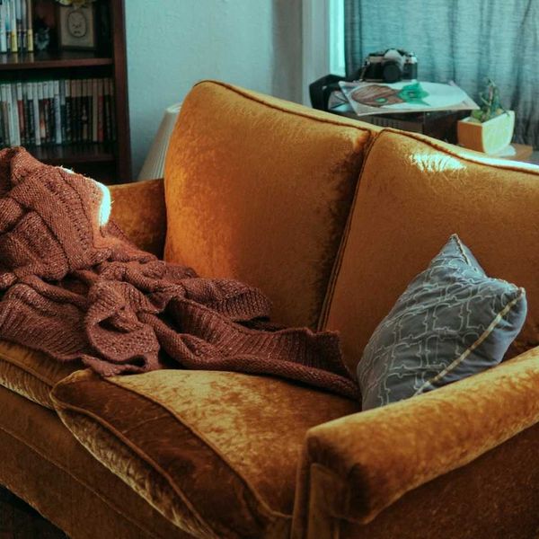 Old brown sofa in cluttered room