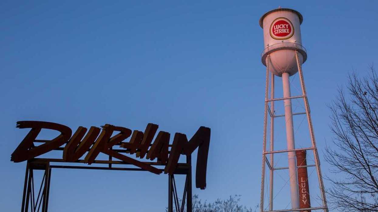 Old water tower with "Lucky Strike" logo on tank adjacent to "Durham" sign