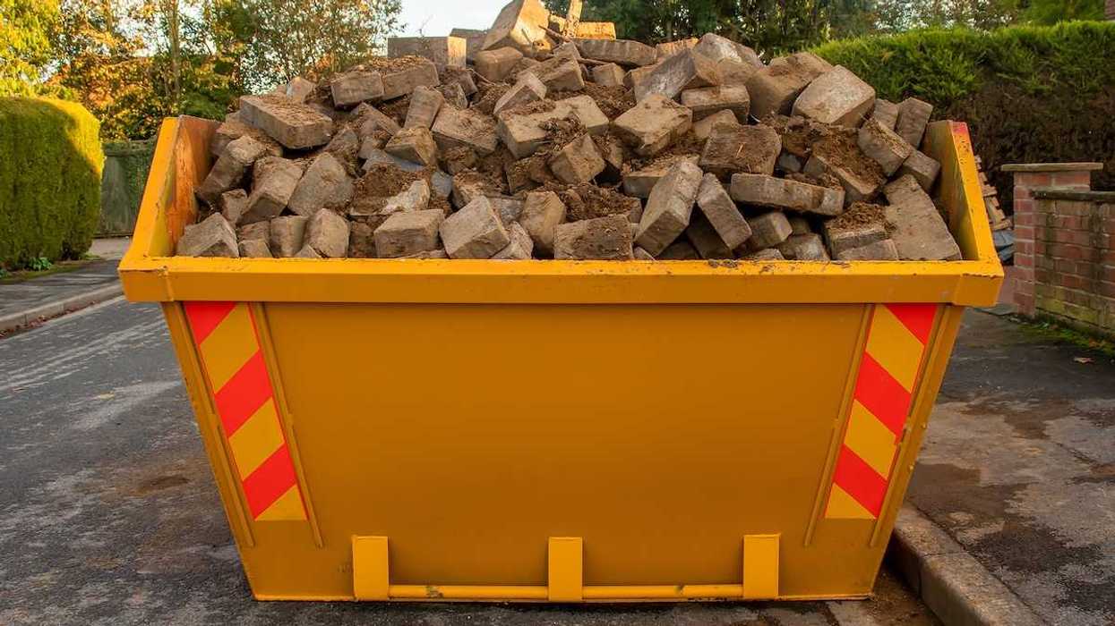 Orange dumpster full of bricks and rubble