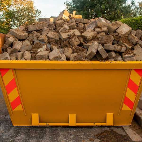 Orange dumpster full of bricks and rubble