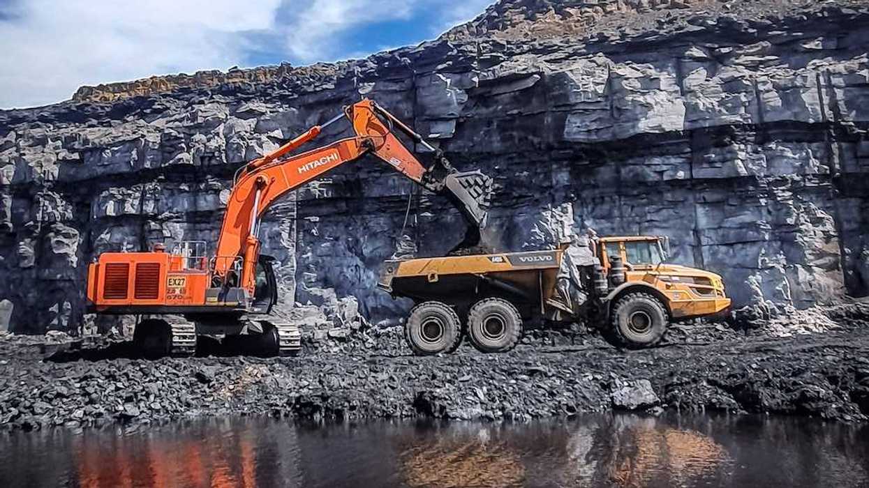 Orange excavator loading yellow rock truck at coal mine