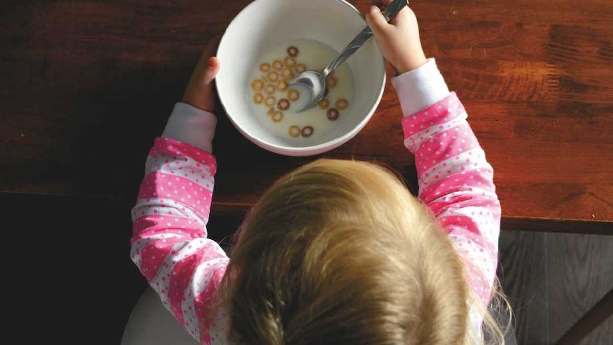 overhead shot of blonde girl eating a bowl of cheerios and milk