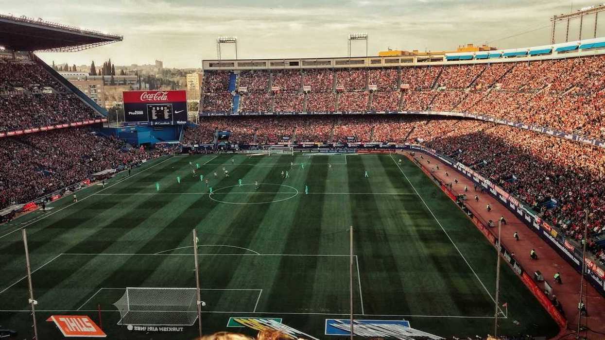 Packed soccer stadium with signage advertising various corporate sponsors