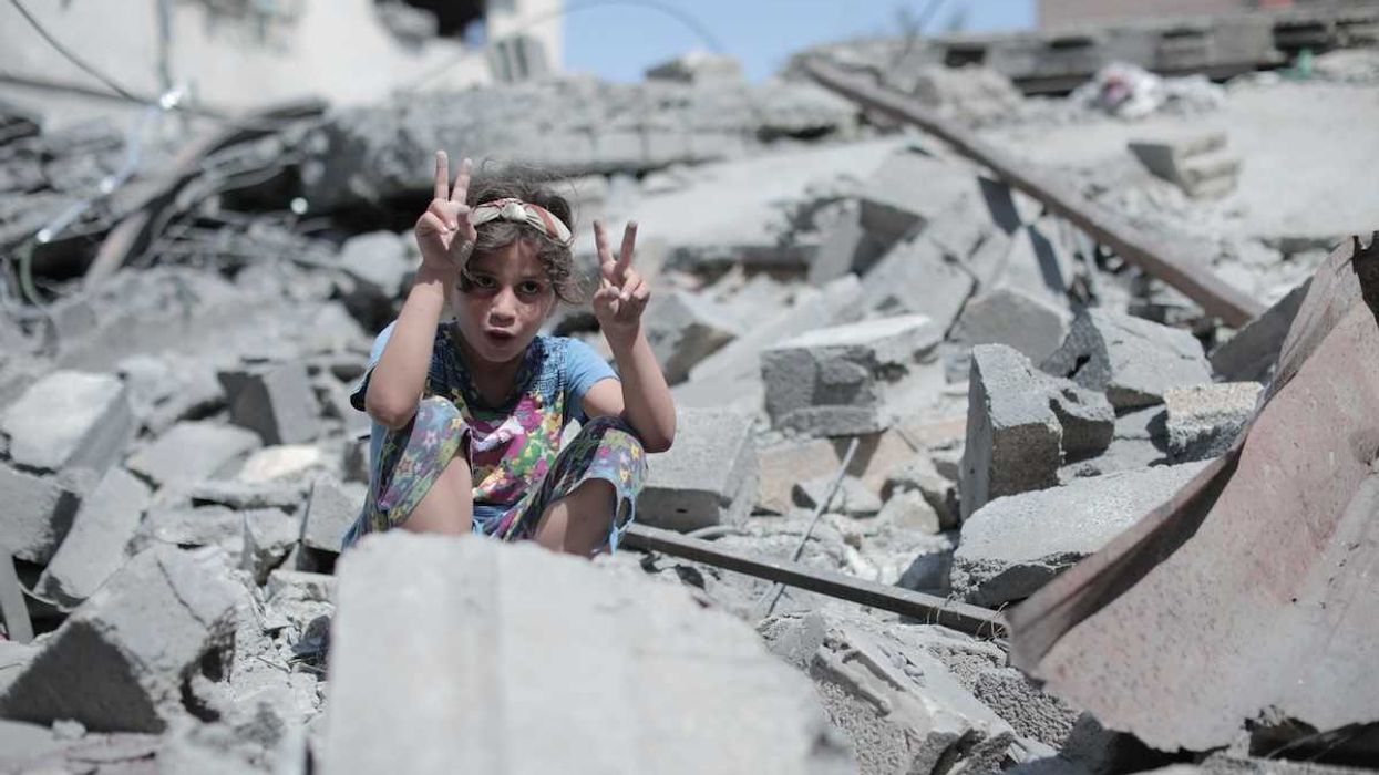 Palestinian boy atop Gaza rubble flashing peace signs