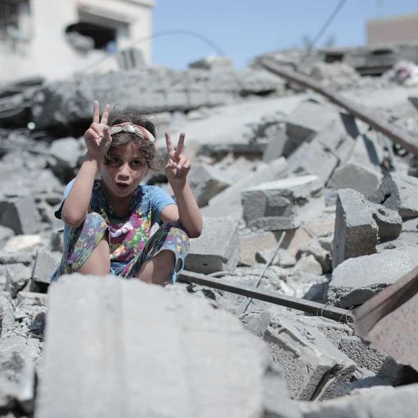Palestinian boy atop Gaza rubble flashing peace signs