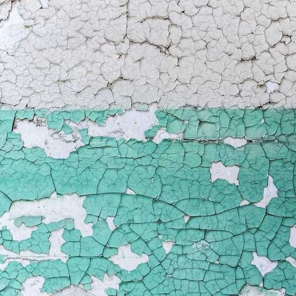 Peeling white and teal-colored paint