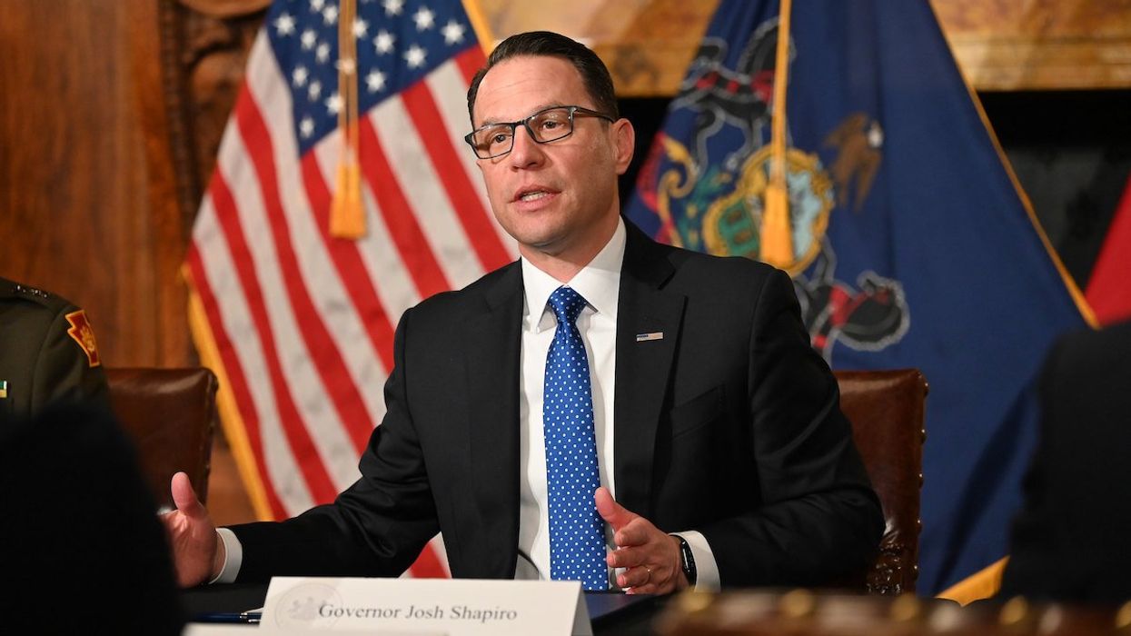 Pennsylvania governor Josh Shapiro speaks with the state flag and American flag behind him.