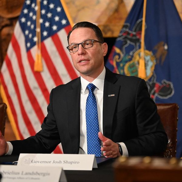 Pennsylvania governor Josh Shapiro speaks with the state flag and American flag behind him.