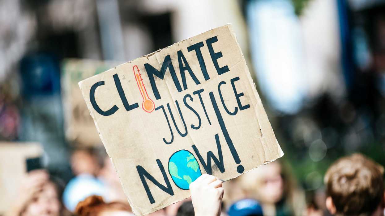 people gathered outside buildings holding Climate Justice Now signage.