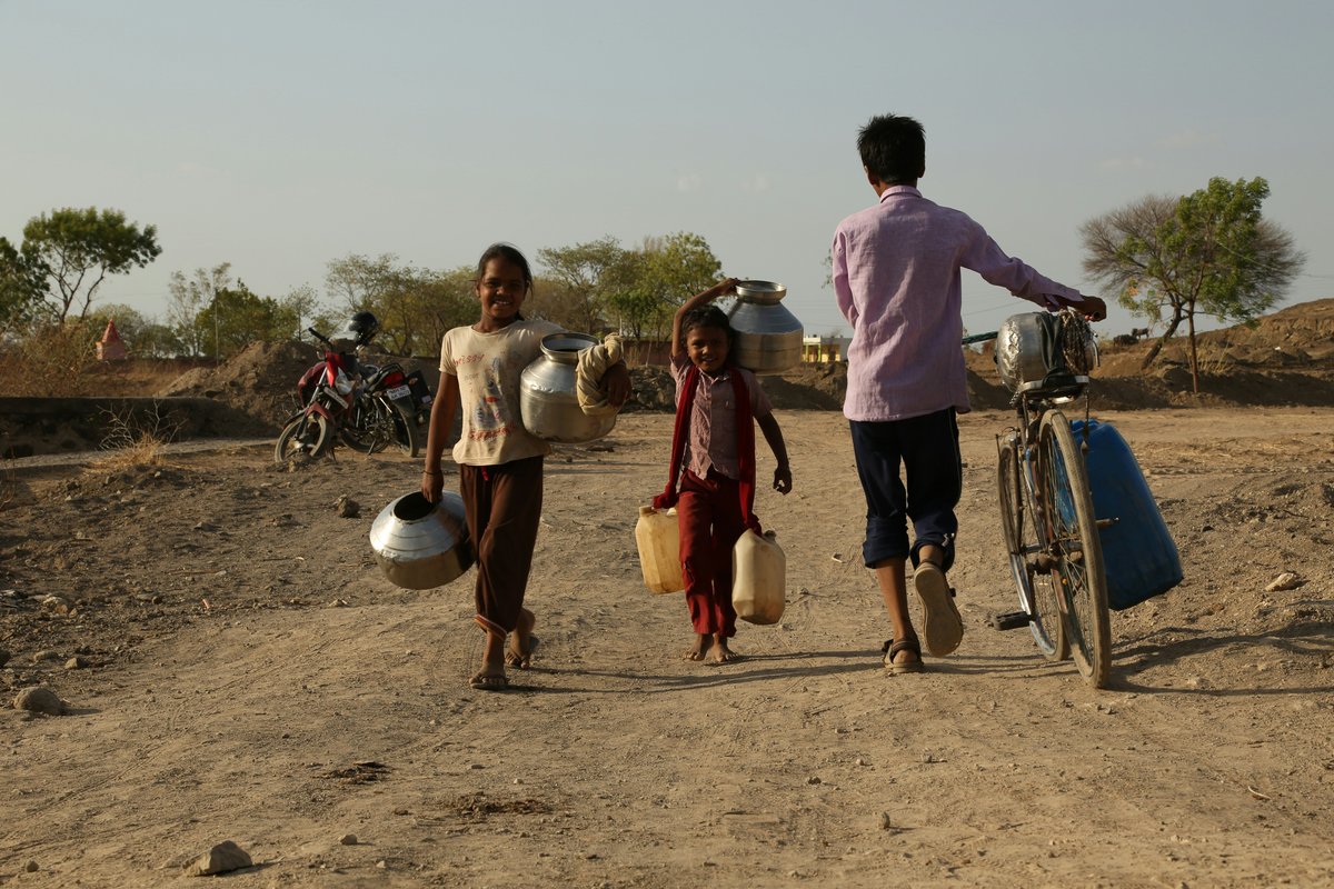 people hauling water on dry dirt road