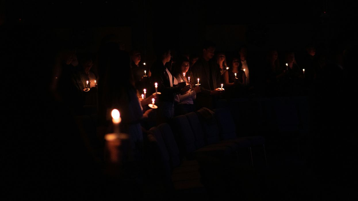 people holding candles in the dark during a vigil.